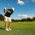 man in black shirt and white shorts playing golf during daytime